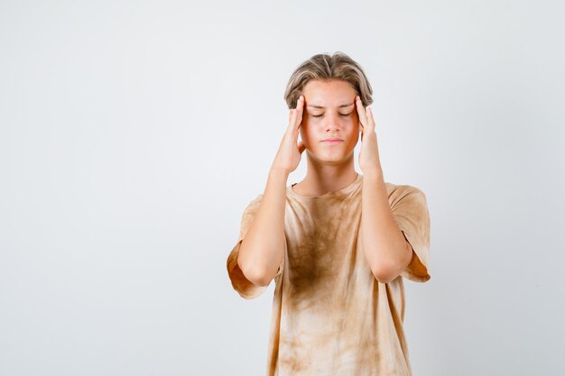 Portrait of teenager boy suffering from migraine in t-shirt and looking exhausted front view