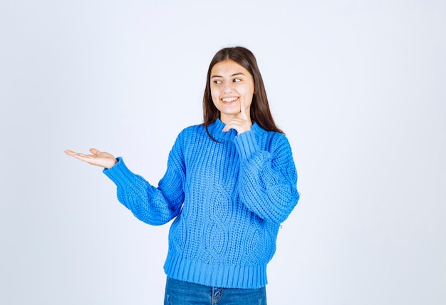 Portrait of teenager girl in blue sweater standing and showing open space.