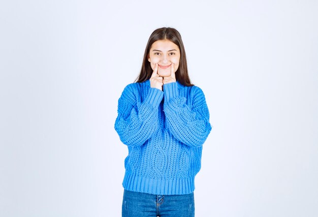 Portrait of teenager girl in blue sweater standing and showing smile.