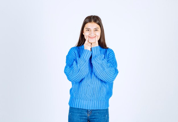 立って笑顔を見せて青いセーターのティーンエイジャーの女の子の肖像画。