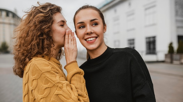 Free photo portrait of a teenager whispering in her friends ear