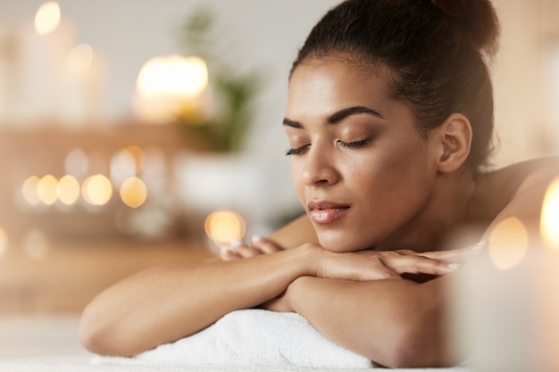 Portrait of tender african woman with closed eyes resting relaxing in spa resort.