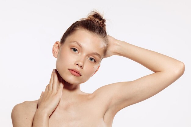 Portrait of tender beautiful young girl with nude makeup posing isolated over white studio background Natural beauty