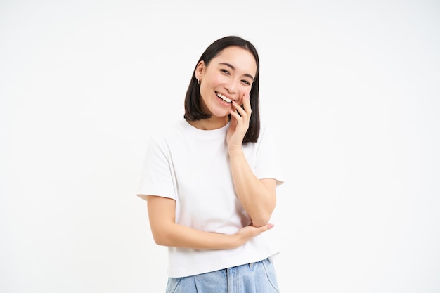 Free photo portrait of tender cute young asian woman looking with flirty silly ace expression standing over whi