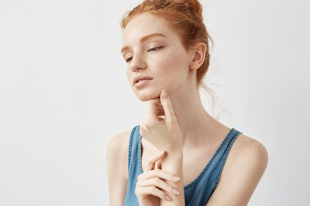 Portrait of tender redhead model posing with closed eyes.