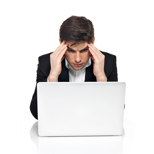 Portrait of thinking office worker with laptop having stress sitting on table, isolated on white.