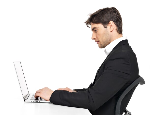Портрет мышления молодой офисный работник с ноутбуком, сидя на столе, изолированном на белом.