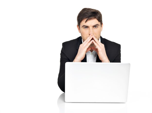 Портрет мышления молодой офисный работник с ноутбуком, сидя на столе, изолированном на белом.