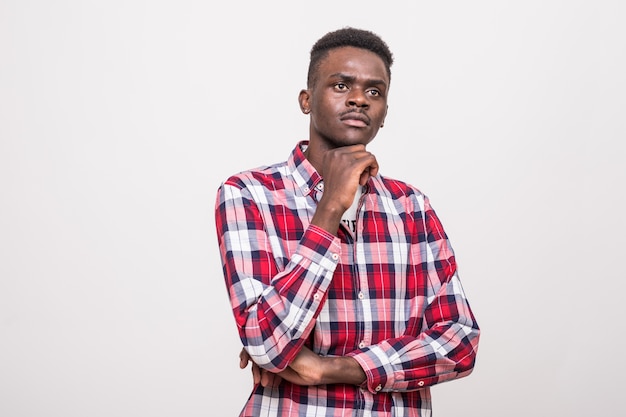 Portrait of a thoughtful afro american man standing with hand on chin and looking away isolated