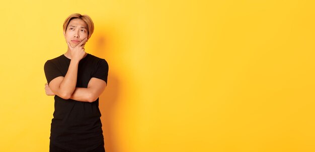 Portrait of thoughtful attractive guy in black tshirt looking upper left corner young man pondering