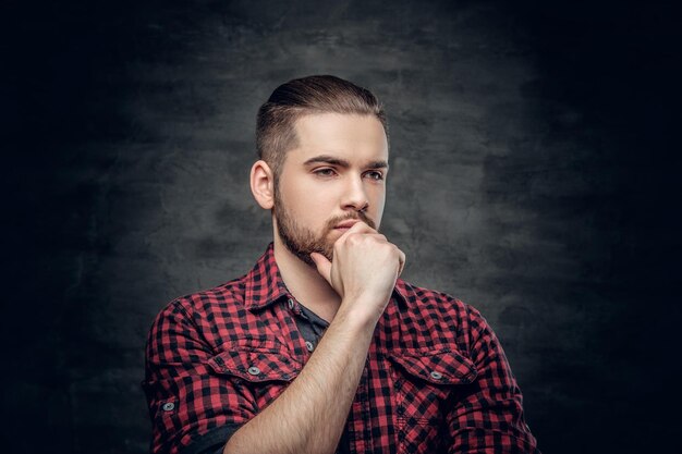 Portrait of thoughtful bearded male dressed in a red fleece shirt over grey background.