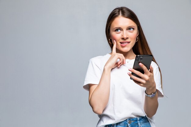 Portrait of a thoughtful doubtful asian woman talking on mobile phone and looking up isolated