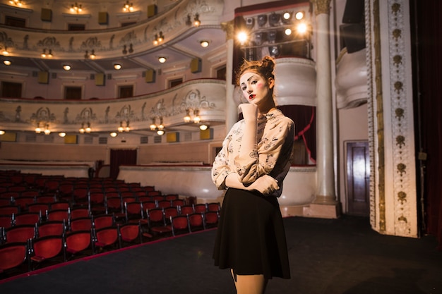 Portrait of thoughtful female mime artist standing on stage