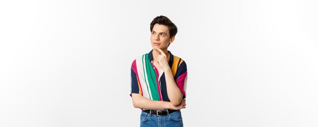 Portrait of thoughtful queer man in stylish shirt looking at upper left corner and thinking making c