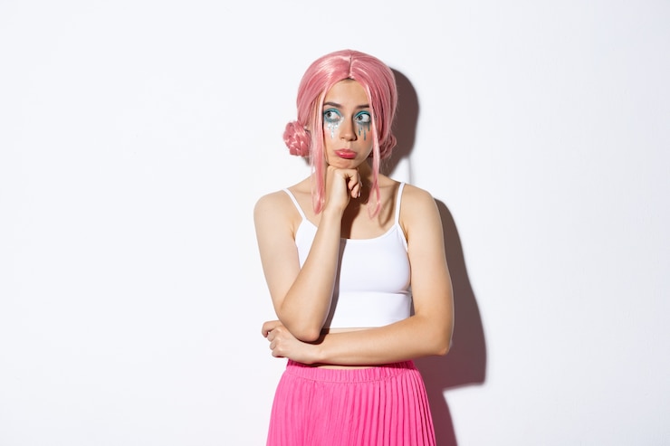 Free Photo portrait of thoughtful sad girl with pink hair and bright makeup, wearing halloween outfit, looking left and pouting upset, standing.