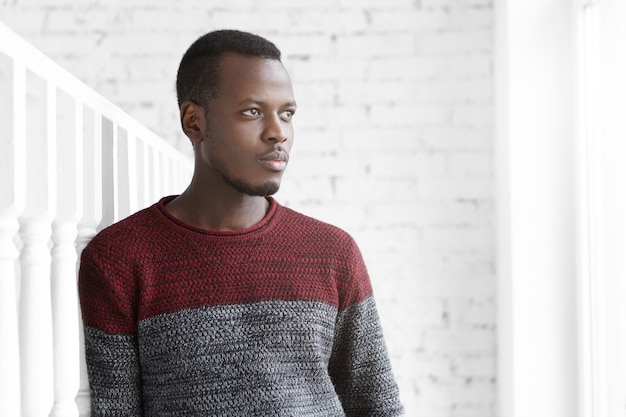 Portrait of thoughtful young Afro-American engineer dressed casually standing in white room