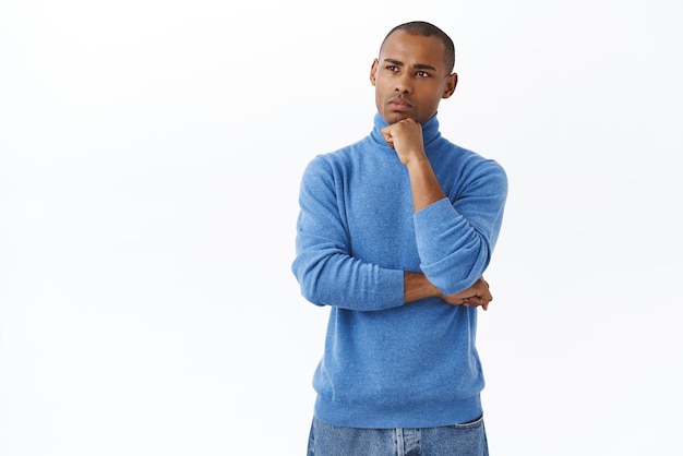 Portrait of thoughtful young focused africanamerican man thinking making decision choosing something hold hand over chin look away pondering have tough choice white background