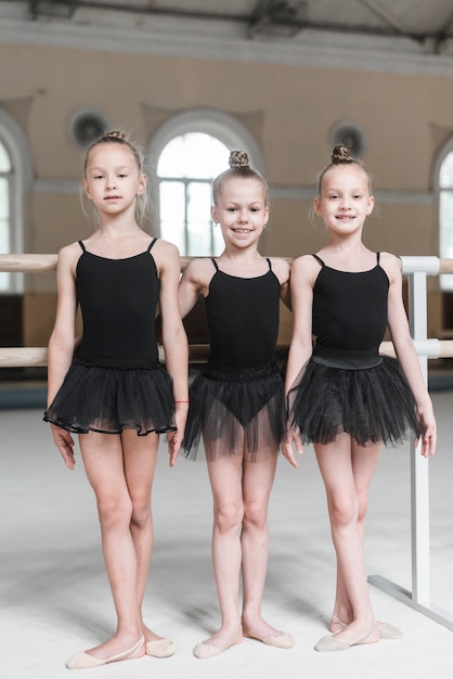 Foto gratuita un ritratto di tre ragazze della ballerina che si levano in piedi nello studio di ballo