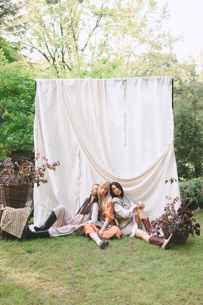 Portrait of three beautiful women at garden, sitting on the ground during daytime.