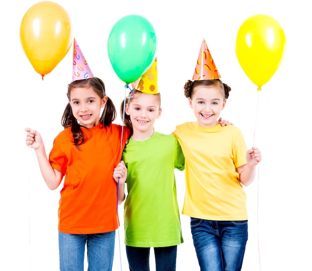 Foto gratuita ritratto di tre bambine sveglie con palloncini colorati e cappello da festa - isolato su un bianco.