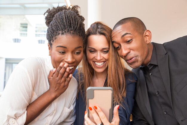 Портрет трех счастливых деловых людей, смеющихся над мобильным видео