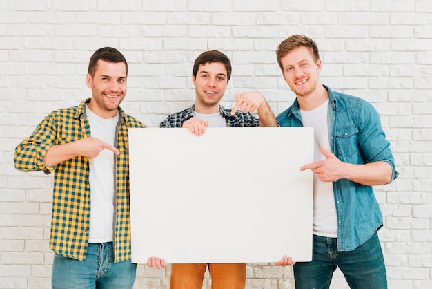 白い空白のプラカードを示す3人の男性の友人の肖像画