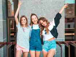 Foto gratuita ritratto di tre giovani belle ragazze sorridenti hipster in abiti estivi alla moda. donne spensierate sexy in posa sulla strada. divertimento di modelli positivi