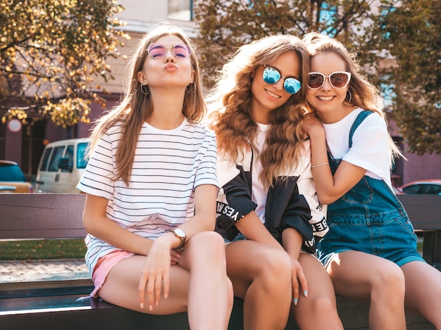 トレンディな夏服の3人の若い美しい笑顔流行に敏感な女の子の肖像画。路上でポーズをとってセクシーな屈託のない女性。サングラスで楽しんでいるポジティブなモデル。