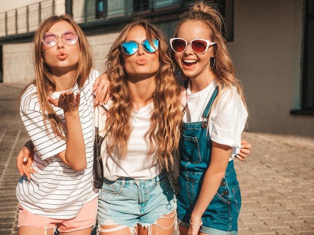 Portrait of three young beautiful smiling hipster girls in trendy summer clothes. Sexy carefree women posing on the street.Positive models having fun in sunglasses.Making duck face