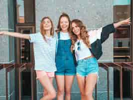 Free photo portrait of three young beautiful smiling hipster girls in trendy summer clothes. sexy carefree women posing on the street.positive models having fun.they raise hands