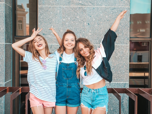 トレンディな夏服の3人の若い美しい笑顔流行に敏感な女の子の肖像画。セクシーな屈託のない女性が路上でポーズします。