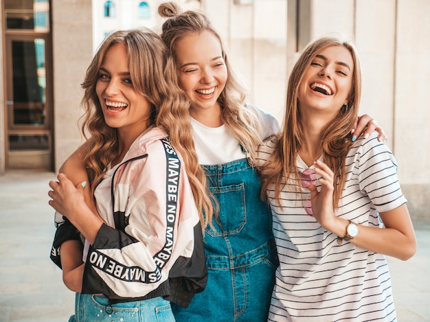 Foto gratuita ritratto di tre giovani belle ragazze sorridenti hipster in abiti estivi alla moda. donne spensierate sexy che posano per strada. divertimento dei modelli positivi