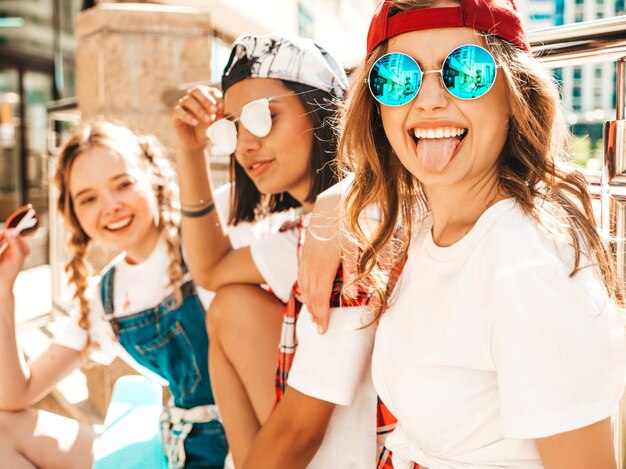 Portrait of three young beautiful smiling hipster girls in trendy summer clothes.