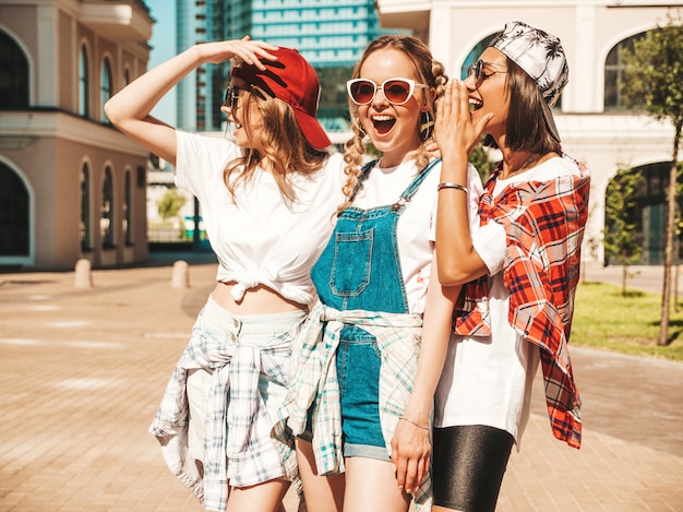 Portrait of three young beautiful smiling hipster girls in trendy summer clothes