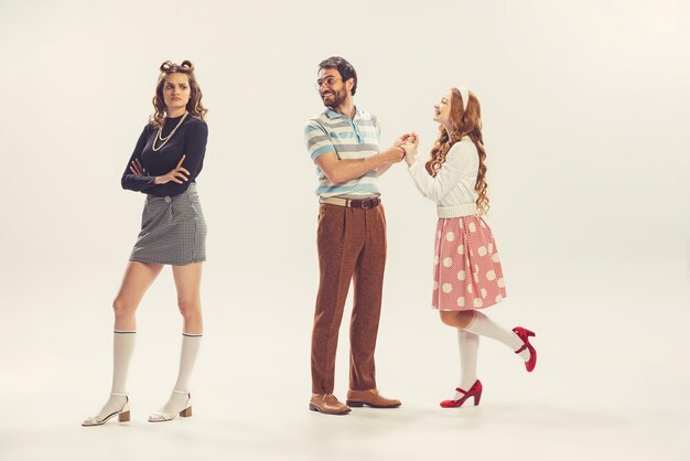 Portrait of three young people posing talking isolated over white studio background Retro style