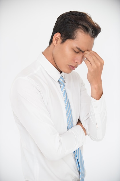 Portrait of tired young businessman rubbing eyes