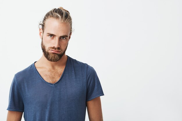 Portrait of tired young man with stylish hairstyle and beard