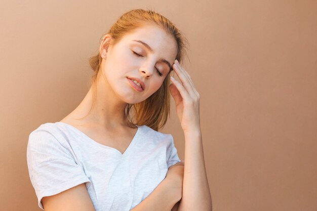 Portrait of a tired young woman against brown background