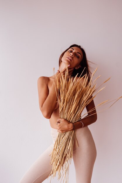 Portrait of topless woman in fitting leggings holding wild dried flowers