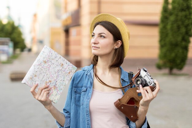 Portrait of tourist holding camera and local map