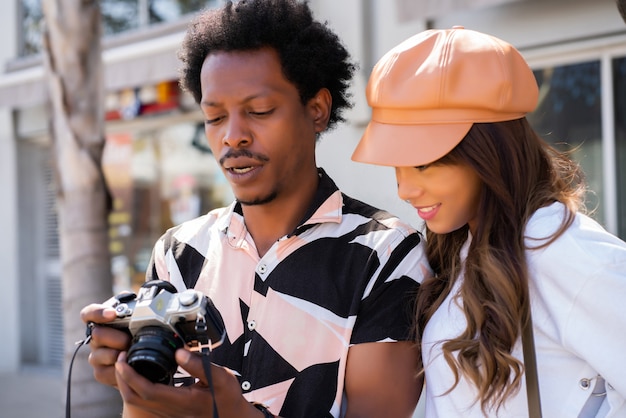 Portrait of tourist young couple using camera and taking photographs in the city