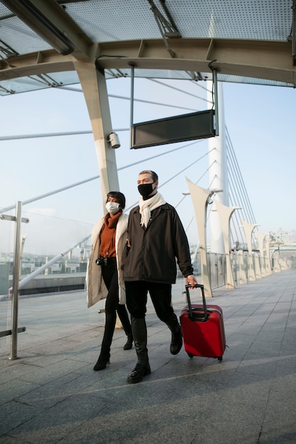 Free photo portrait of tourists with medical masks and luggage