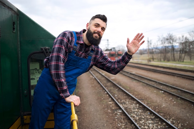 Ritratto del macchinista del treno o della locomotiva agitando alla stazione