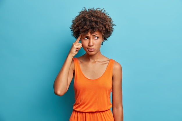 Foto gratuita ritratto di giovane e bella donna afroamericana dispiaciuta turbata tiene il dito sulla tempia