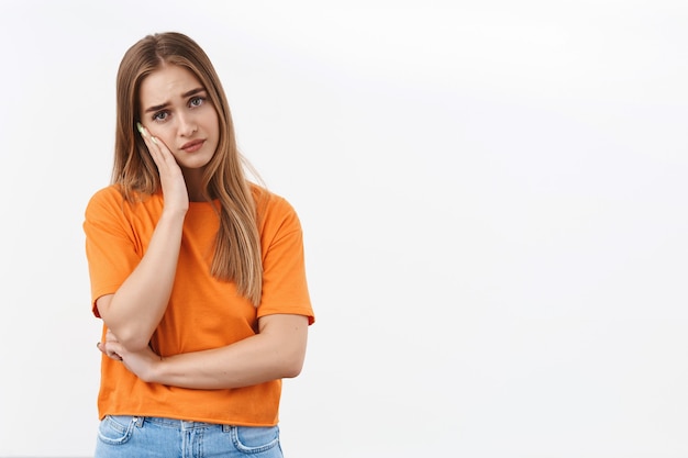 Foto gratuita ritratto di una donna bionda preoccupata e pensierosa bloccata in una situazione difficile, si sente a disagio e frustrata, sospirando