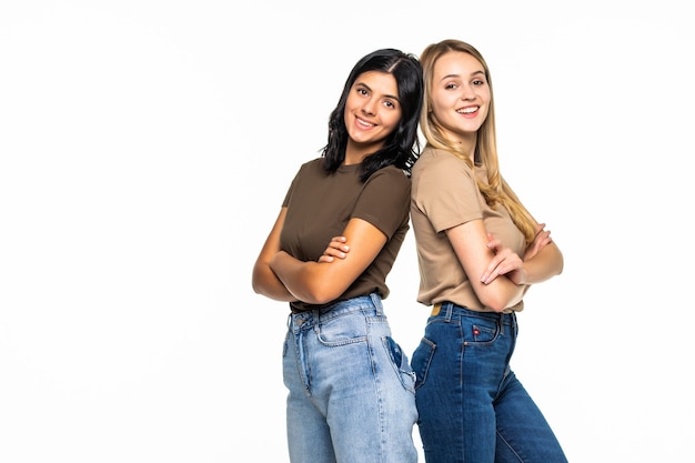 Free photo portrait of a two beautiful girls standing back to back isolated on a white wall