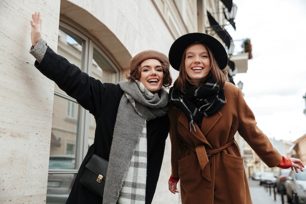 Portrait of two cheery girls dressed in autumn clothes walking