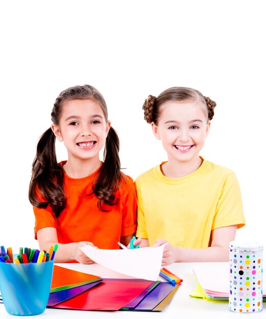 Portrait of two cute little girls in colourful t-shirt cut scissor cardboard - isolated on white.