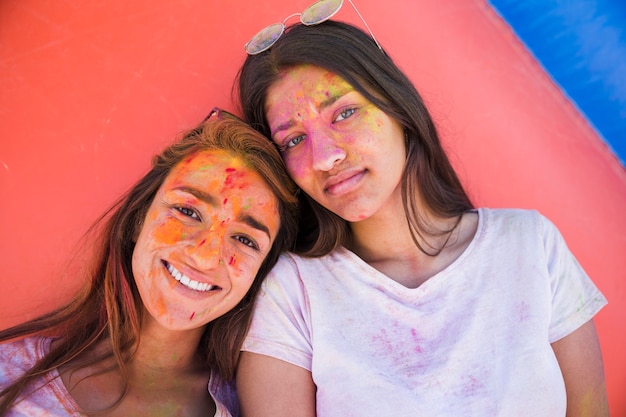 Portrait of two female friends with holi colors on their face