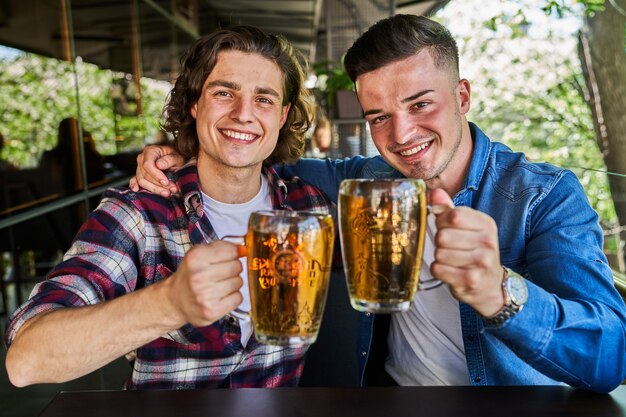 Portrait of two friends in pub drinking beer.